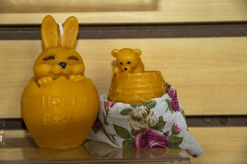An Easter bunny candle beside a bear honey pot