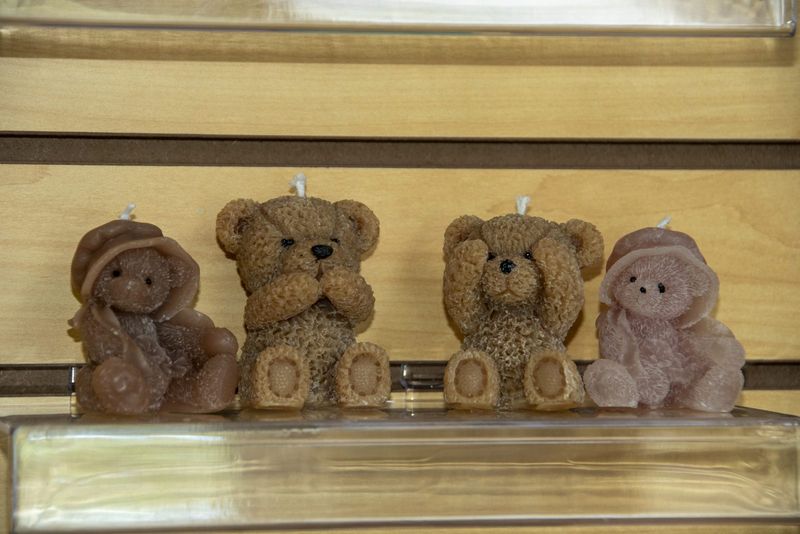 Four teddy bear candles lined up on a shelf
