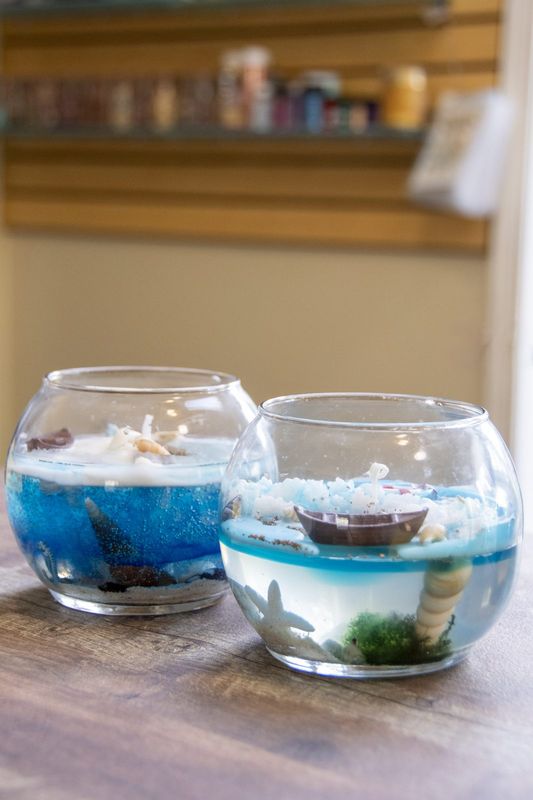 Two round gel candles holding tiny boats and starfish
